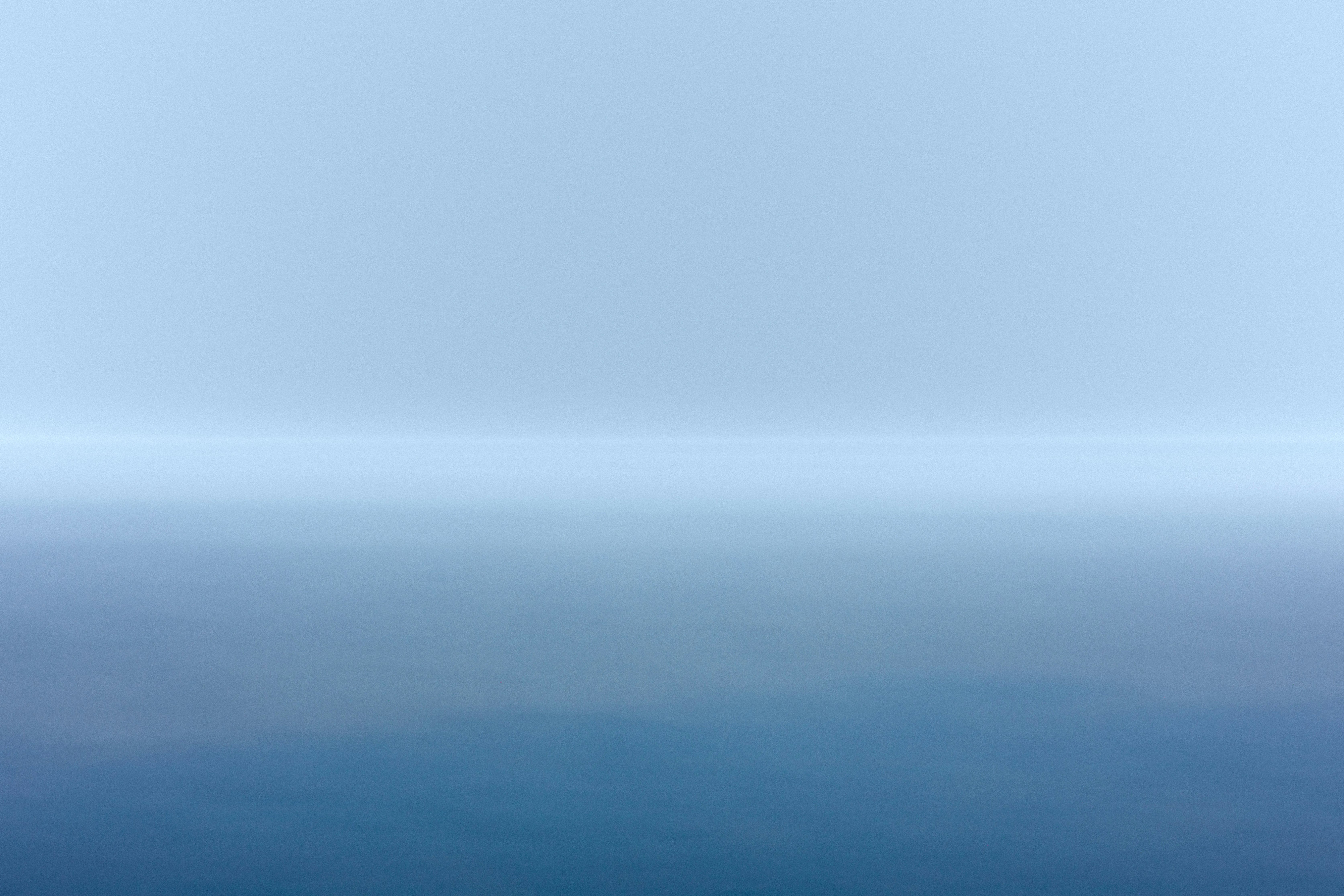 blue body of water under white sky during daytime